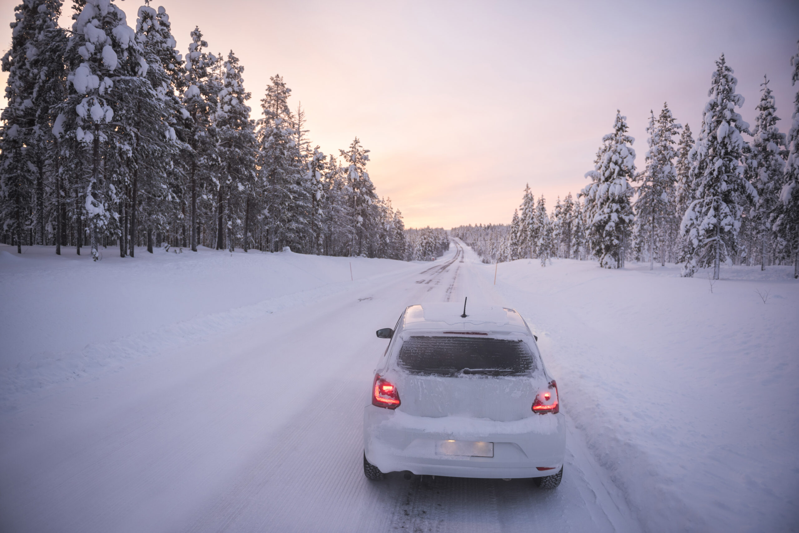 Car driving on icy snow covered roads on a road trip while travelling in Lapland inside the Arctic C